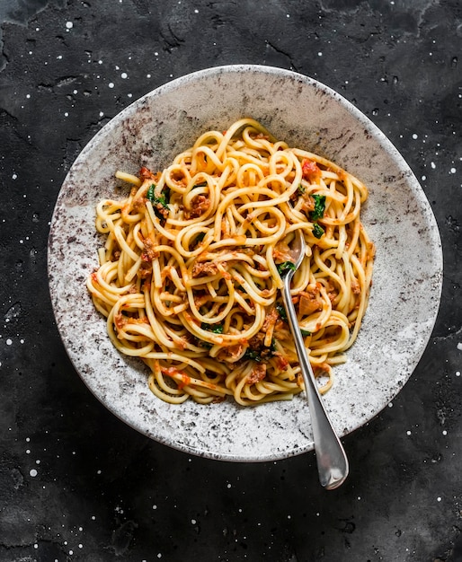 Spaghetti mit Tomatenkonserven-Thunfischsoße auf einer Draufsicht des dunklen Hintergrundes