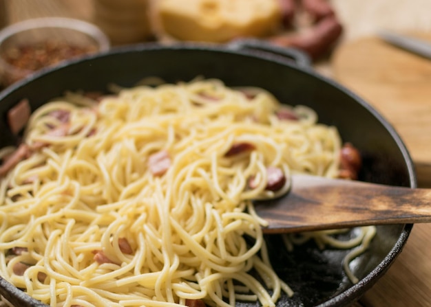 Spaghetti mit Wurstkäse und Wachteleiern in einer Bratpfanne