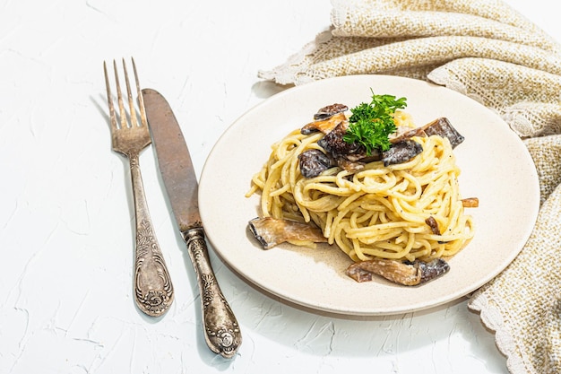 Spaghetti-Nudeln mit Austernpilz-Sahnesauce und Petersilie, gesundes veganes Essen, verzehrfertig, trendiger harter, heller, dunkler Schatten, weißer Hintergrund in Nahaufnahme