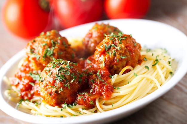 Spaghetti-Nudeln mit Fleischbällchen in Tomatensauce und Kräutern auf einem weißen Teller