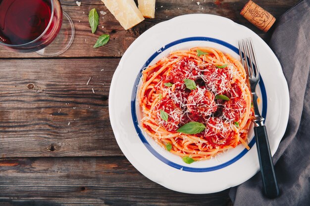 Spaghetti-Nudeln mit Fleischbällchen Tomatensauce und Parmesan-Käse auf Holzhintergrund