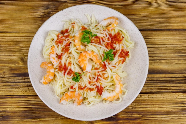 Spaghetti-Nudeln mit Garnelen, Tomatensauce und Petersilie auf Draufsicht des Holztischs