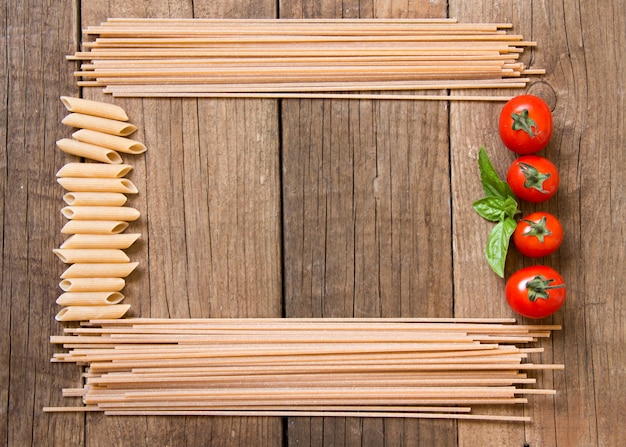 Spaghetti-Nudeln, Tomaten und Basilikum auf hölzernem Hintergrund Draufsicht