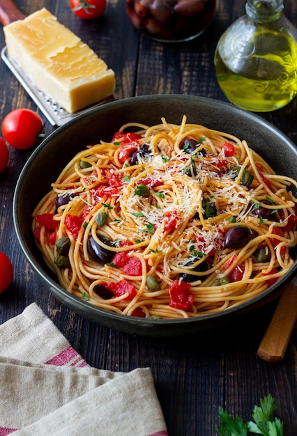 Spaghetti Pasta Alla Puttanesca mit Kapern Kalamata Oliven Käse Tomaten und Sardellen italienisches Essen