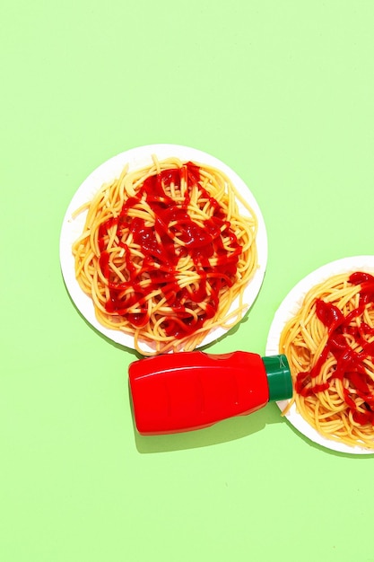 Spaghetti Pasta mit Ketchup auf grünem Hintergrund Minimalistische Diät Kalorien italienisches Essen Kunstkonzept