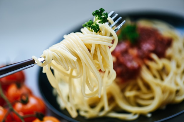 Spaghetti en tenedor y spaghetti pasta italiana boloñesa con perejil en el restaurante comida italiana y menú