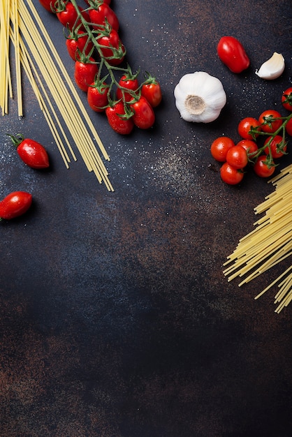 Spaghetti, Tomate und Knoblauch auf dem schwarzen Tisch