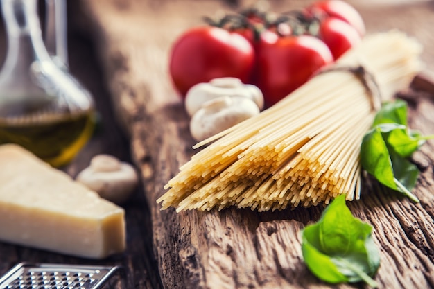 Spaghetti Tomaten Basilikum Olivenöl Parmesan und Champignons auf sehr altem Eichenbrett