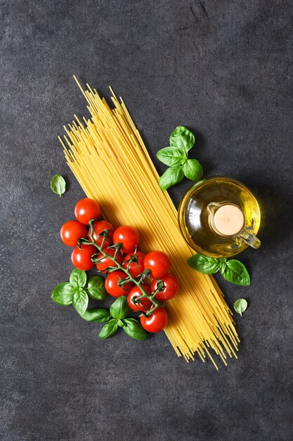 Spaghetti, Tomaten und Basilikum auf schwarzem Beton