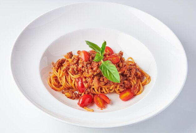 Spaghetti Tomatensauce mit Zerkleinertem Schweinefleisch Bolognese Top mit Basilikumblättern auf weißem Hintergrund