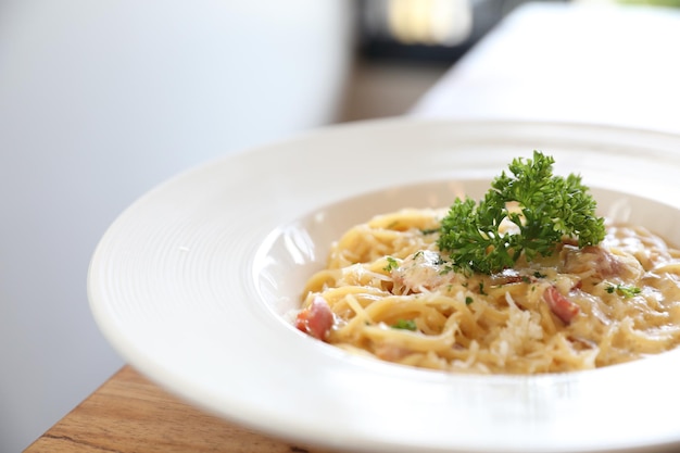 Spaghetti weiße Soße (Spaghetti Carbonara) mit Speck und Knoblauch, auf Holztischhintergrund