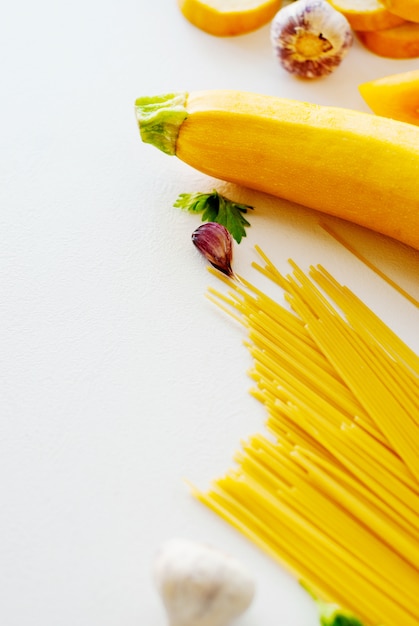 Spaghettis mit gelber Zucchini, Tomate, Knoblauch, Champignon, Petersilie auf weißer Hintergrundebenenlage