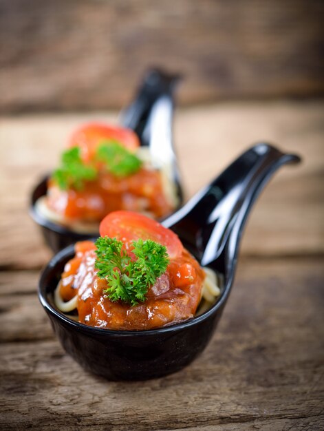 Spaghettis mit Tomatensauce auf Holztisch.