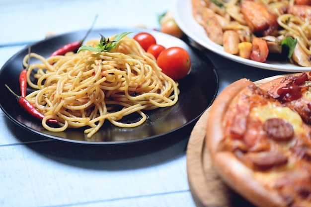 Spaghettiteigwaren und -pizza auf italienischem lebensmittelspaghettis bewohner von bolognese des hölzernen behälters auf platte