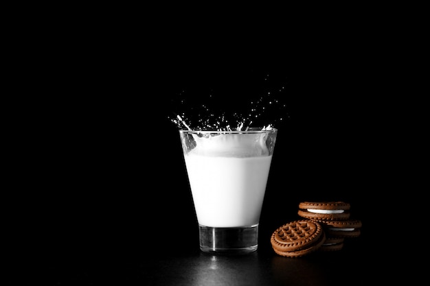 Spalsh im Glas Milch- und Schokoladenplätzchen auf Schwarzem