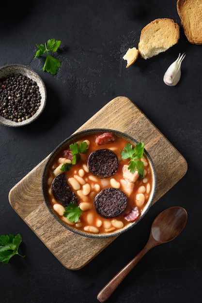 Spanische Asturiana Fabada mit Chorizo und Morcilla auf schwarzem Hintergrund