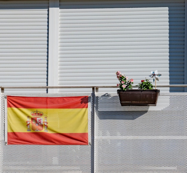 Spanische Flagge auf einem weißen Balkon und einem Grundstück mit Blumen