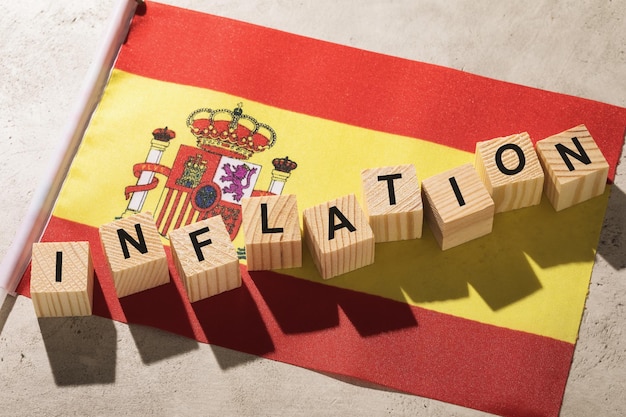Spanische Flagge und Holzwürfel mit Textkonzept zum Thema Inflation in Spanien