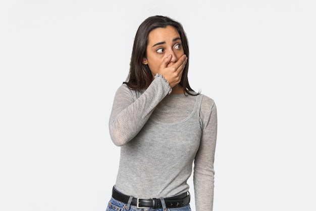Spanische junge Frau, die nachdenklich zu einem Kopierraum schaut und den Mund mit der Hand bedeckt