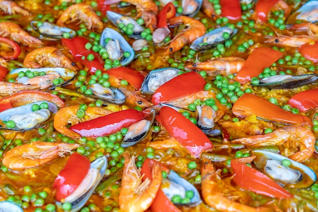 Spanische Paella mit Meeresfrüchten in Bratpfanne mit Muscheln, Garnelen und Gemüse Paella mit Meeresfrüchten im Hintergrund, Nahaufnahme, traditionelles spanisches Reisgericht