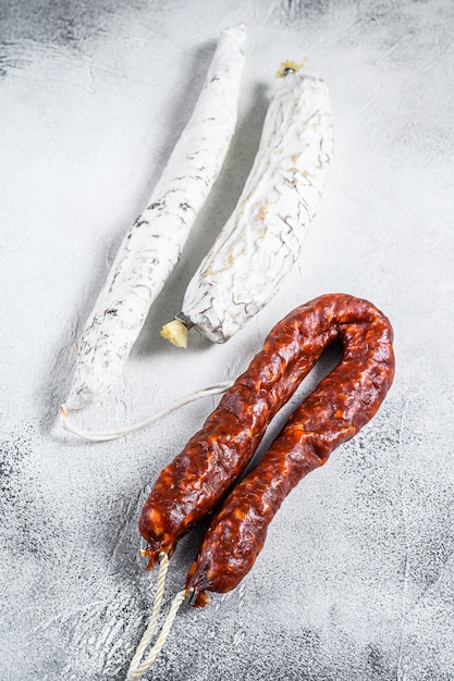 Spanische Salami, Fuet und Chorizo-Würstchen auf einem Küchentisch. Weißer Hintergrund. Ansicht von oben.