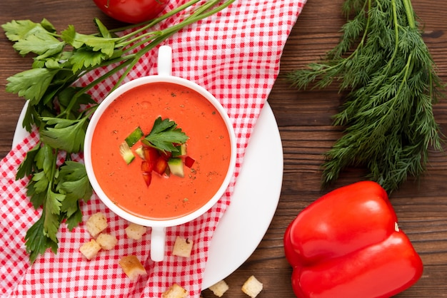 Spanische Tomaten-Gazpacho-Suppe aus frischen Tomaten mit verschiedenen Gewürzen und Kräutern auf hölzernem Hintergrund.