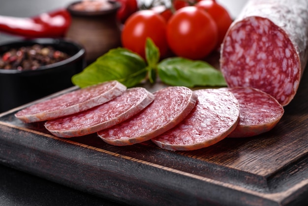 Spanische Trockenwurstsalami auf dunklem Betonhintergrund. Zubereitung von leckeren frischen Sandwiches