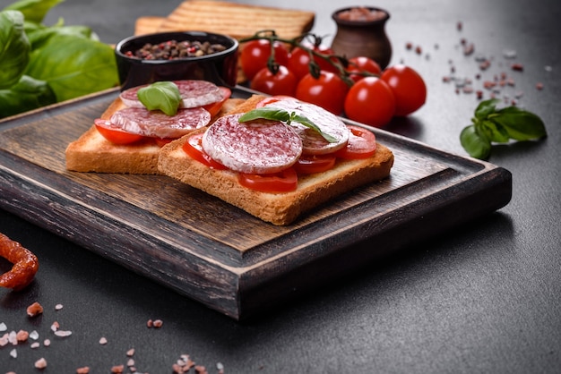 Spanische trockenwurstsalami auf dunklem betonhintergrund. zubereitung von leckeren frischen sandwiches