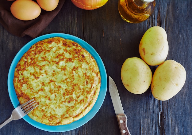 Foto spanisches omelett mit kartoffeln, ei und zwiebeln, begleitet von olivenöl