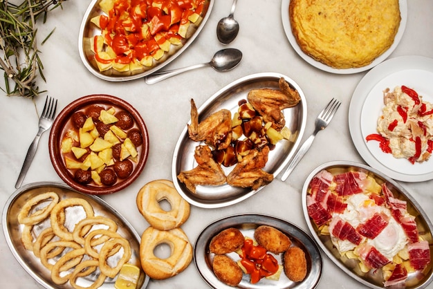 Spanisches Restaurant-Tapas-Set mit Rührei mit iberischem Schinken, gebratenen Hähnchenflügeln, Fleischbällchen mit Kartoffeln, andalusischem Tintenfisch, Kartoffelomelett und Patatas Bravas