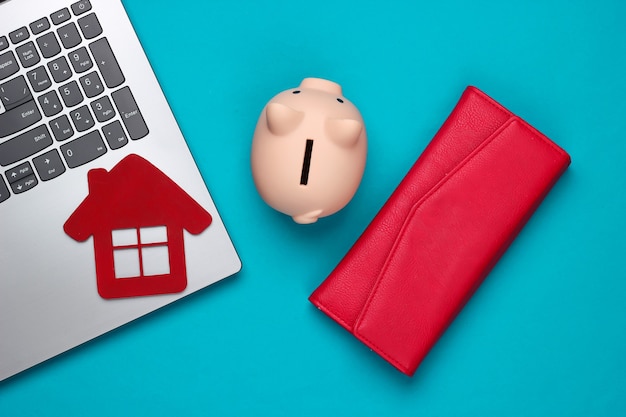 Sparen Sie für die Unterbringung. Laptop, Sparschwein mit Hausfigur, Brieftasche auf blau