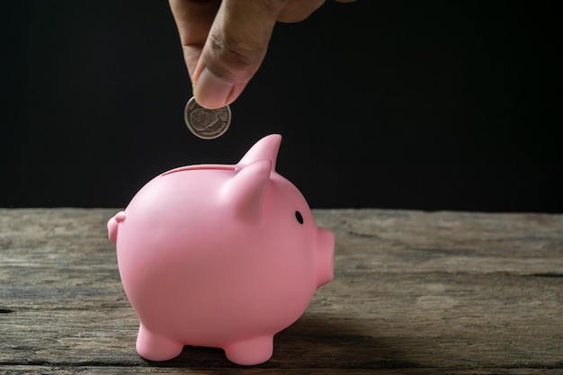 Sparen Sie Geld und Kontobanking für das Finanzkonzept Hand mit Münze auf Sparschwein verschwommenen Hintergrund