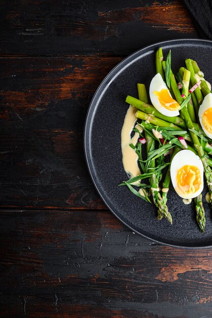 Spargel mit Eiern und französischem Dressing mit Dijon-Senf, Zwiebel gehackt in rotem Essig-Taragon auf altem dunklem Holztisch, Draufsicht mit Platz für Text.