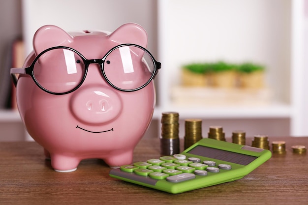 Foto sparschwein in gläsern mit taschenrechner und münzen auf heim- oder bürohintergrund