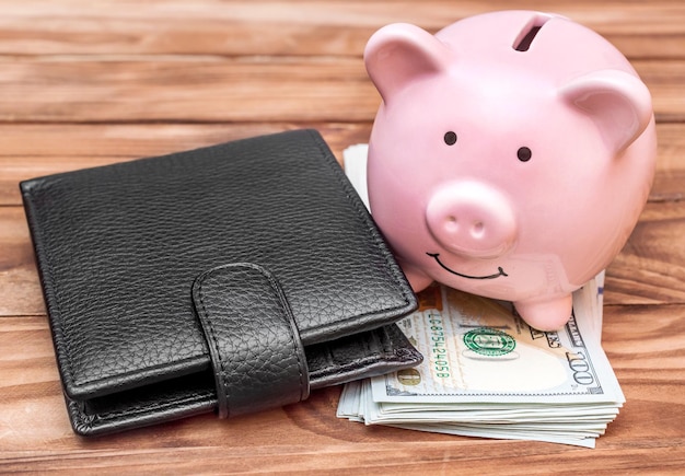 Sparschwein mit Brieftasche und Dollarscheinen auf dem Tisch