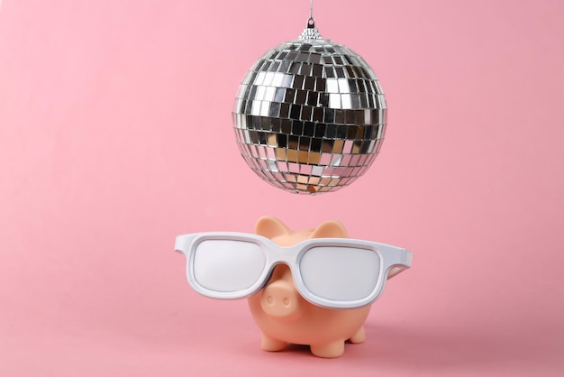 Sparschwein mit Brille unter Discokugel auf rosa Hintergrund Minimalistisches Partykonzept