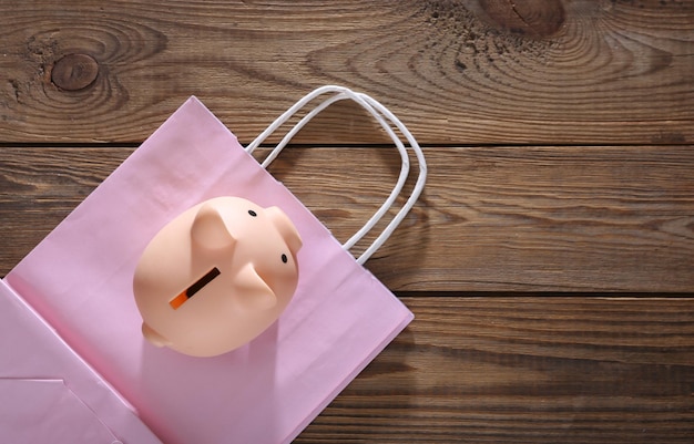 Sparschwein mit Einkaufstasche auf Draufsicht des hölzernen Hintergrundes