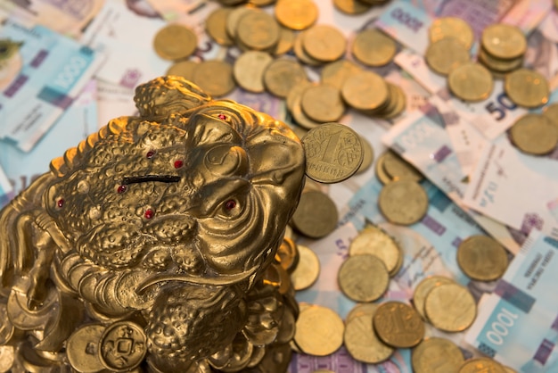 Sparschwein mit Goldmünzen liegt auf ukrainischen Banknoten. 500 und 1000 Griwna. Neu. UAH. Das Konzept der Erhaltung