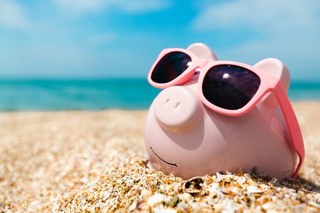 Sparschwein mit Sonnenbrille am Strand entspannen