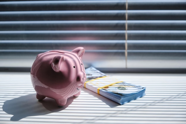 Sparschwein-Stapel von Hundert-Dollar-Scheinen Am frühen Morgen auf der Anhäufung von Windowsill und Erfolgsleben.