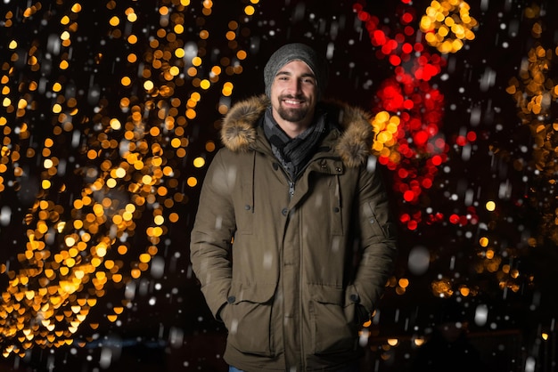 Spaß an einer Weihnachtsfee Junger fröhlicher Mann, der warm gekleidet ist, steht auf dem Weihnachtsmarkt