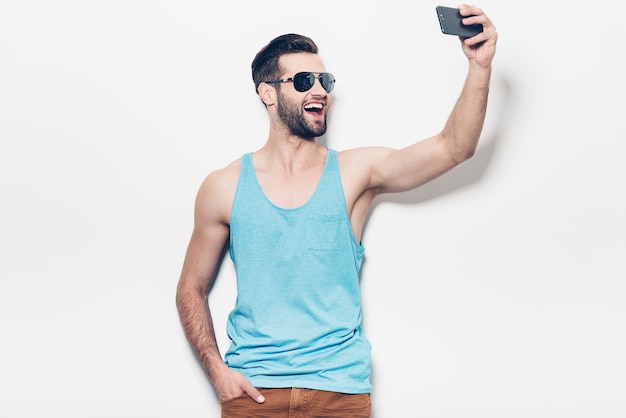 Spaß beim Einfangen. Glücklicher junger gutaussehender Mann mit Sonnenbrille macht Selfie