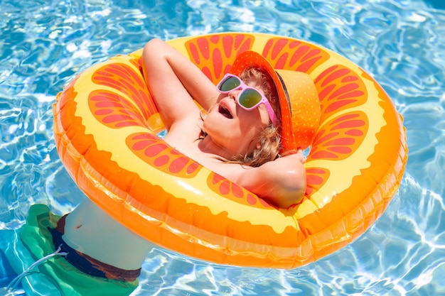 Spaß Kind Porträt Kind im Schwimmbad auf aufblasbaren Ring Kind schwimmen mit orange Schwimmer Wasserspielzeug er
