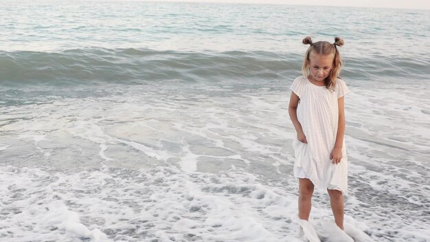 Spaß lächelndes Kleinkind Mädchen barfuß am Küsten Sand Zeit am Meer spielen.