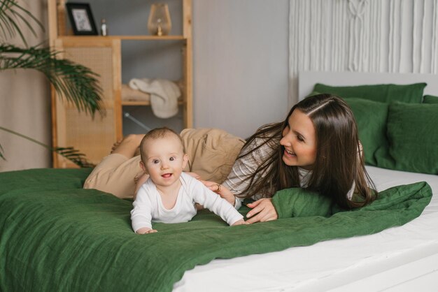 Spaß mit Mama und Baby auf dem Bett zu Hause haben