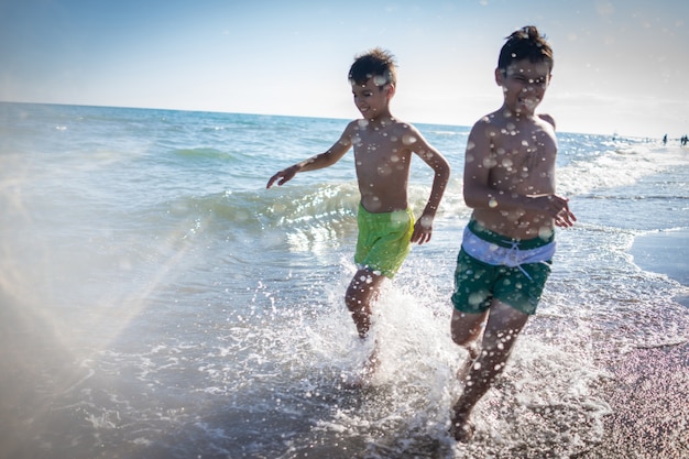 Spaßkinder, die Spritzen am Strand spielen