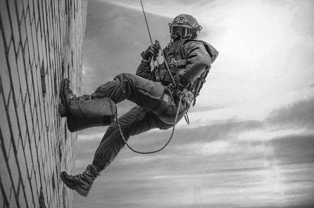 Special Forces Fighter steigt von einem Wolkenkratzer herab, um die Wohnung zu stürmen. SWAT, Polizei, Konzept zur Terrorismusbekämpfung.