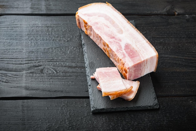 Speck Pancetta geschnitten und in Scheiben geschnitten auf schwarzem Holztisch mit Platz für Text