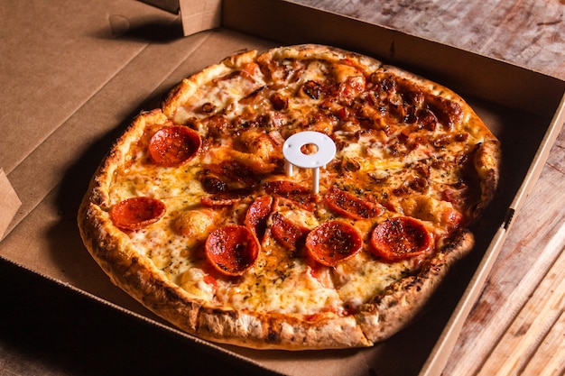 Speck und Peperoni-Pizza auf einem Karton.