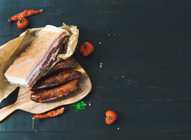 Speck und Wurstwaren auf dunklem Hintergrund. Speicherplatz kopieren.